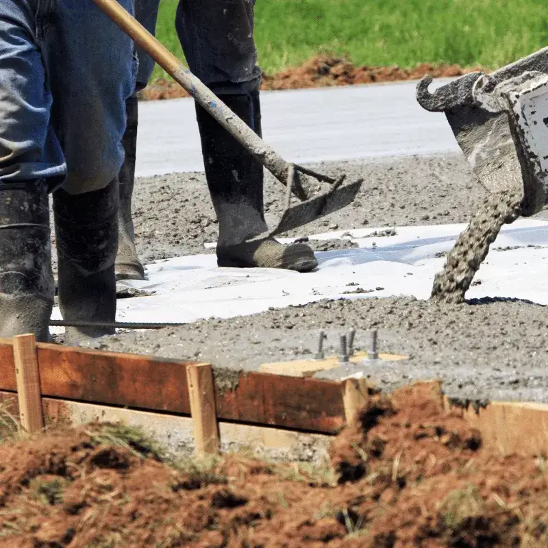 concrete-2 Workers spreading wet concrete with shovels on a construction site for a building foundation.