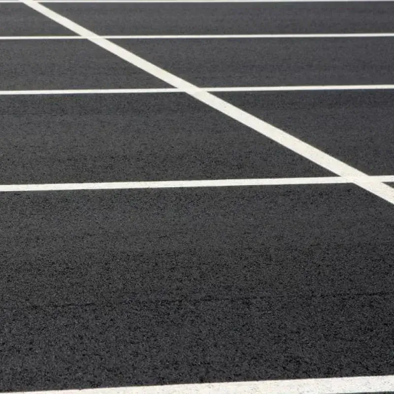 Empty asphalt parking lot with white painted lines marking parking spaces.