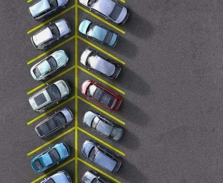 Aerial view of cars parked diagonally along yellow lines in a parking lot with empty space on the right.